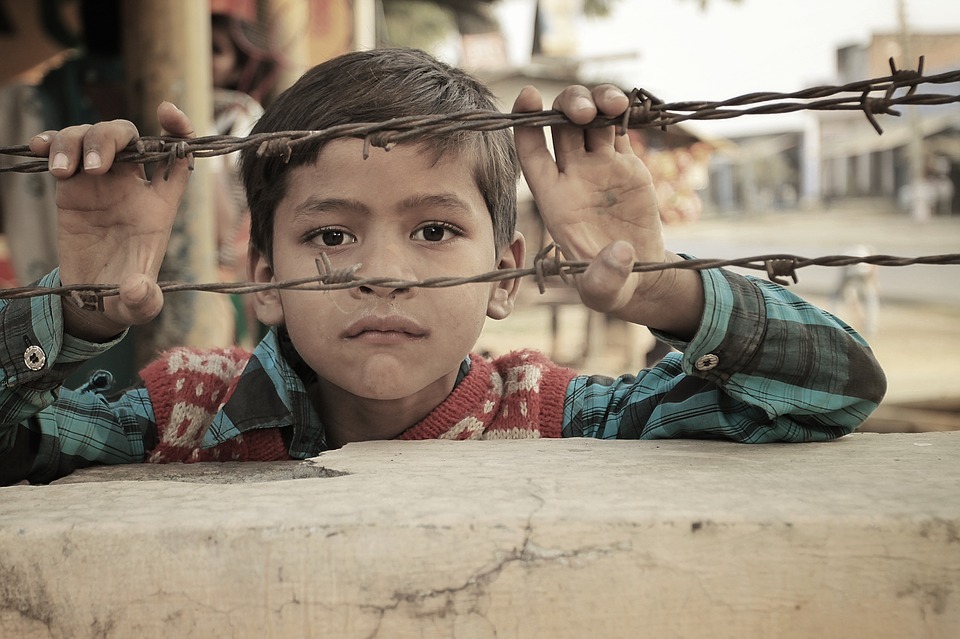 Young boy imprisoned behind barbed wire
