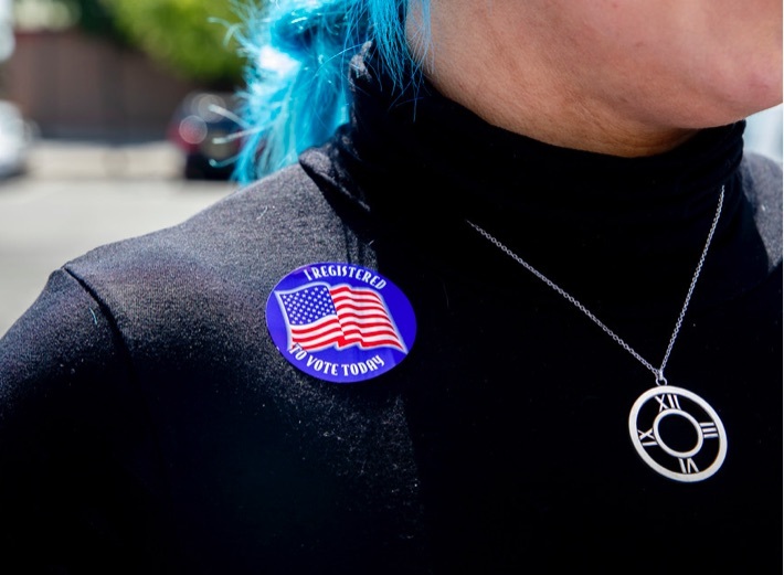 Young woman with sticker that says I registered to vote today
