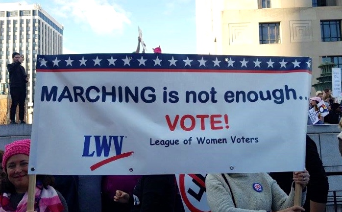 Rally with signs saying Marching Is No Enough - Vote!