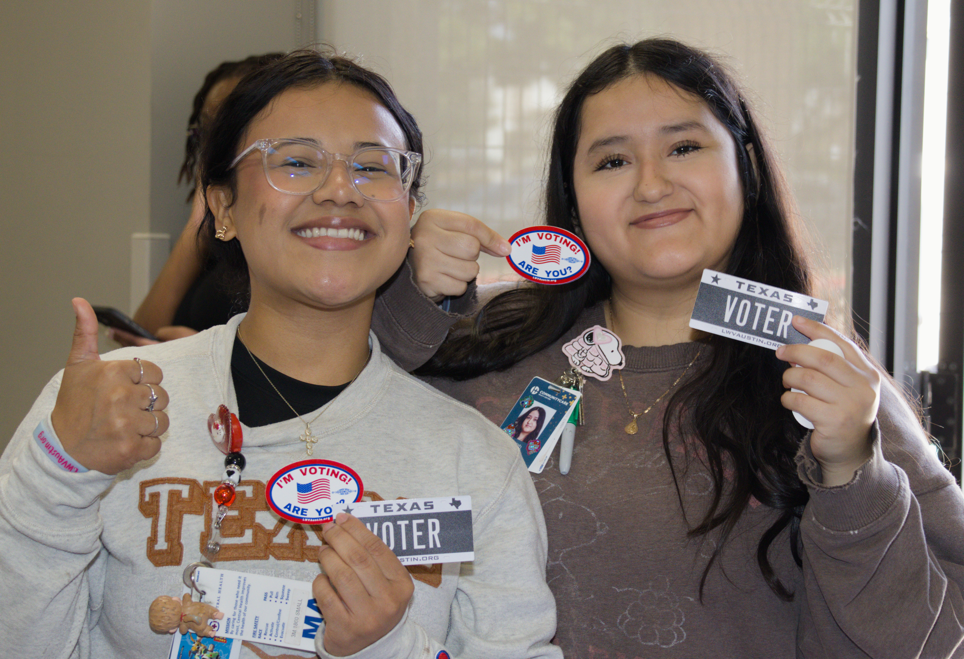 Two young women smiling with vote stickers
