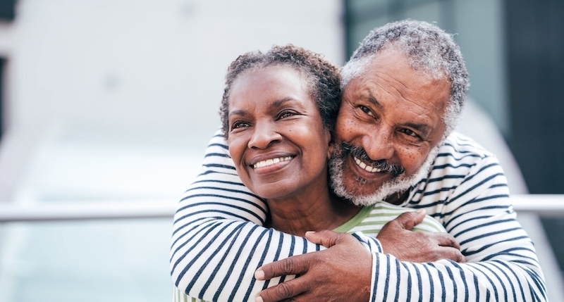 two smiling older aduts embracing. Photo from Sage Collective