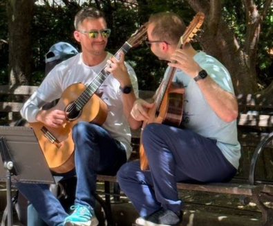 Two men playing acoustic guitar in Goudy Park