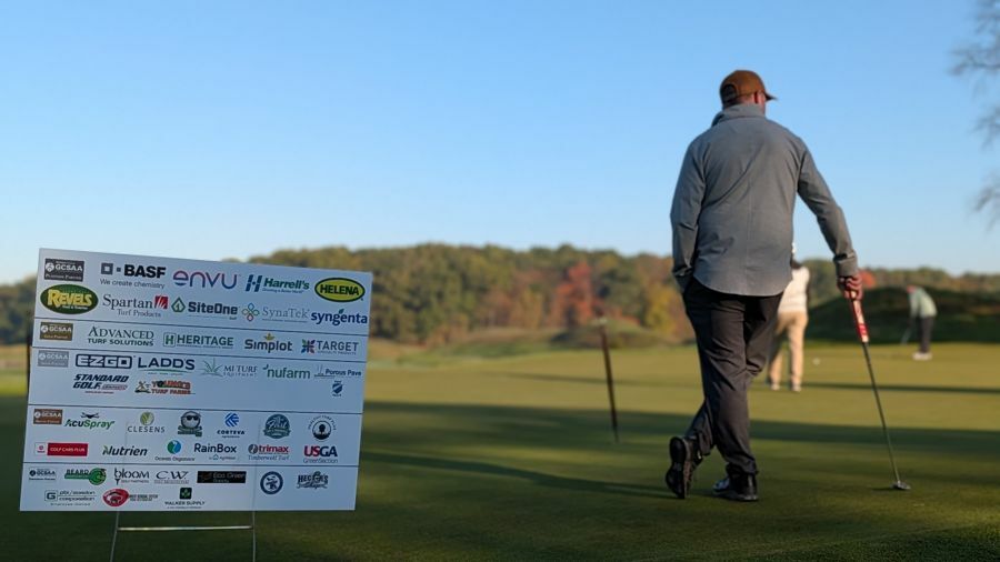 Golfer at the putting green beside the sponsor board