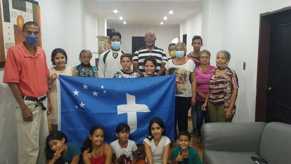 A group of people posing for a photo with the Rock Church flag displayed