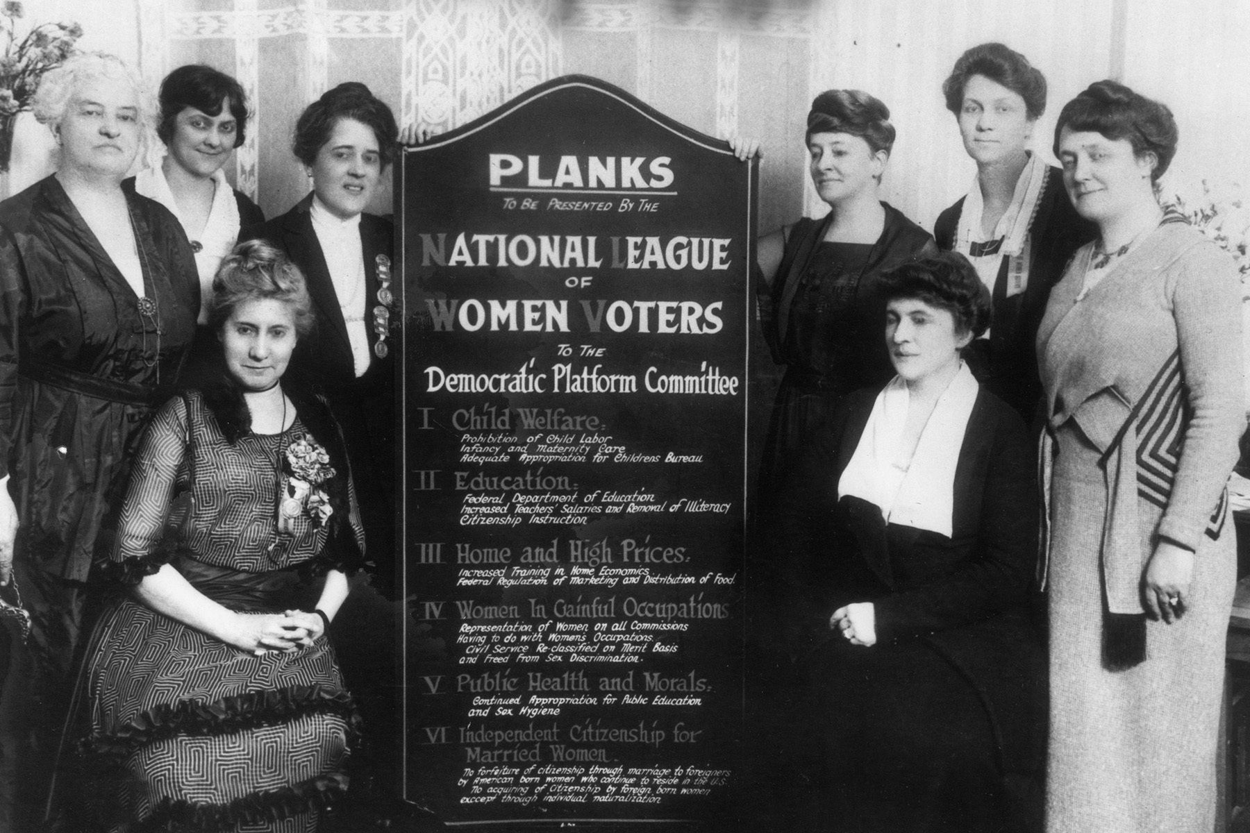 Historic image of League members from 1920 with a large sign listing their planks