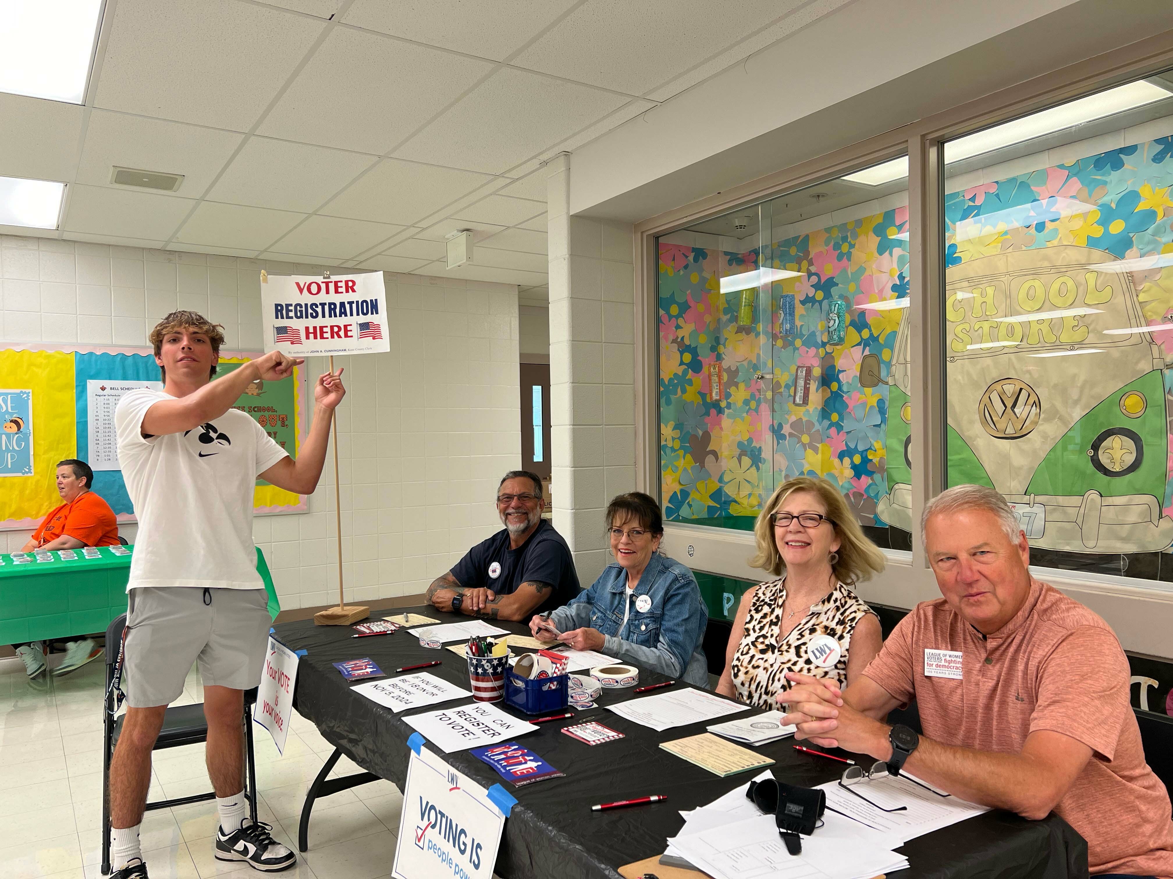 Voter registration table and student holding sign