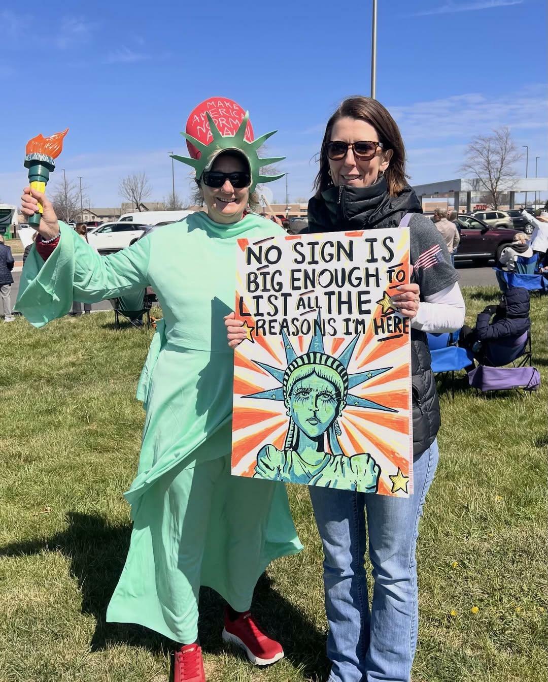 2 people at no kings protest with one dressed as lady liberty