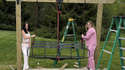 Two women building a ski chairlift swing.